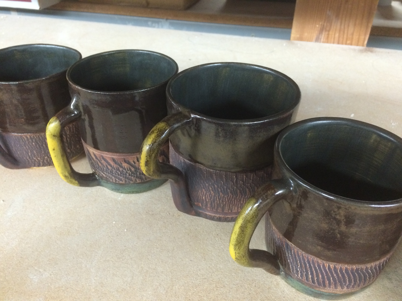 Textured ceramic mugs with iron oxide and charcoal shino glaze